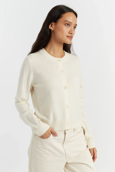 Woman wearing a cream cardigan and pants on a white background