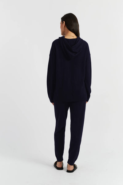 Person wearing a navy blue hoodie and pants on a white background