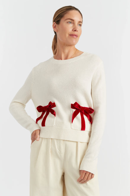 Woman wearing a white sweater with red bows on a white background