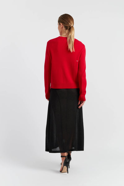 Woman wearing a red sweater and black skirt on a white background