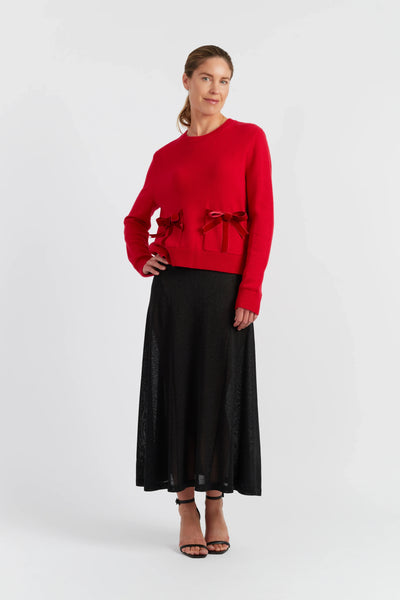 Woman wearing a red sweater with a black skirt on a white background