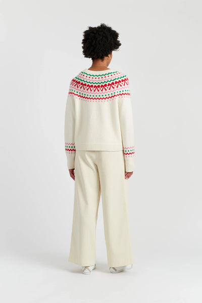 Person wearing a cream sweater with a colorful pattern on the back, standing against a white background