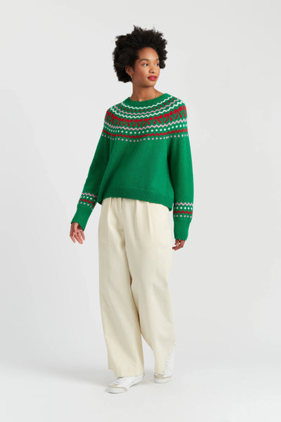 Person wearing a green sweater with a pattern, standing against a white background