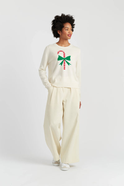 Person wearing a cream-colored outfit with a candy cane and bow design on a white background
