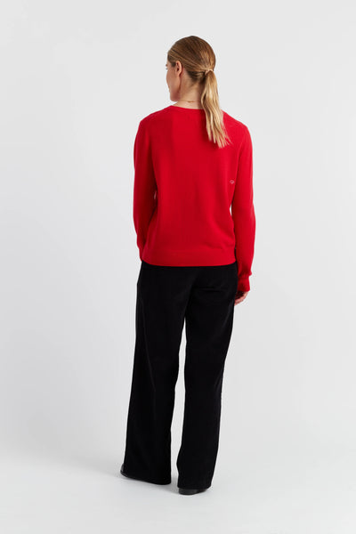 Person wearing a red sweater and black pants on a white background