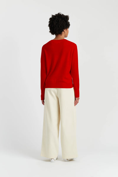 Person wearing a red sweater and white pants on a white background