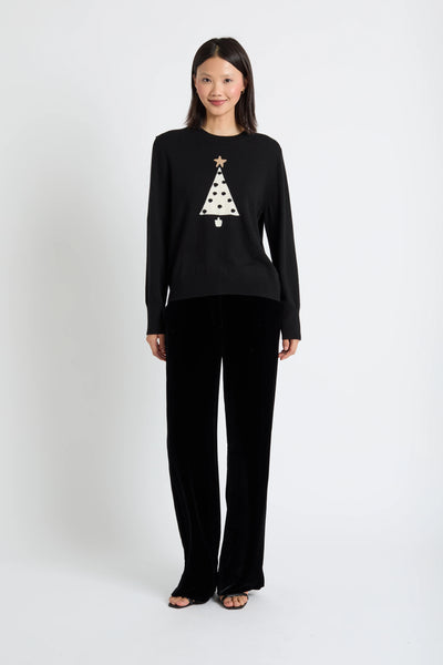 Woman wearing a black sweater with a Christmas tree design on a white background