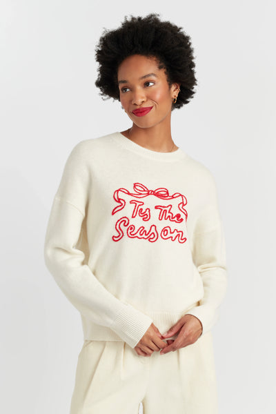 Woman wearing a white sweater with red text on a plain background