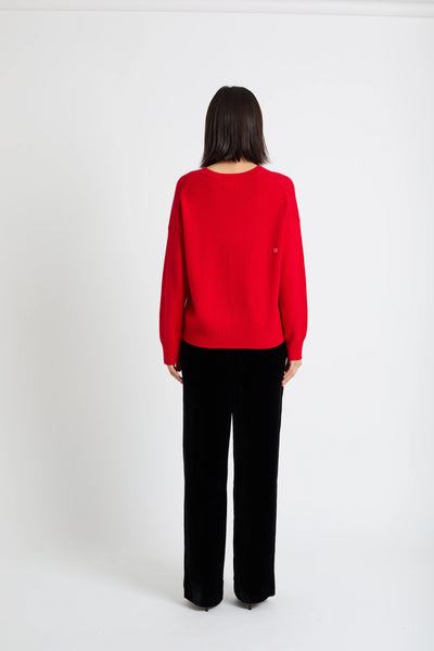 Person wearing a red sweater and black pants on a white background