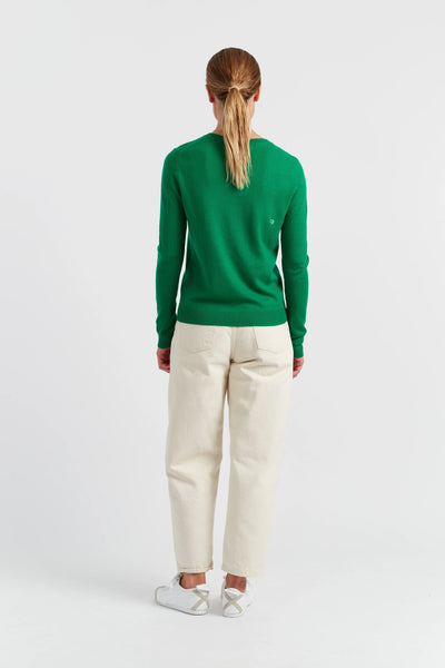 Person wearing a green sweater and white pants on a white background