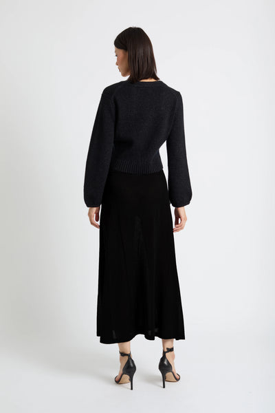 Woman wearing a black outfit with a long skirt on a white background