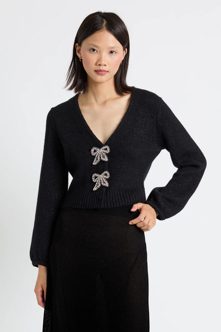 Woman wearing a black sweater with bow embellishments on a white background