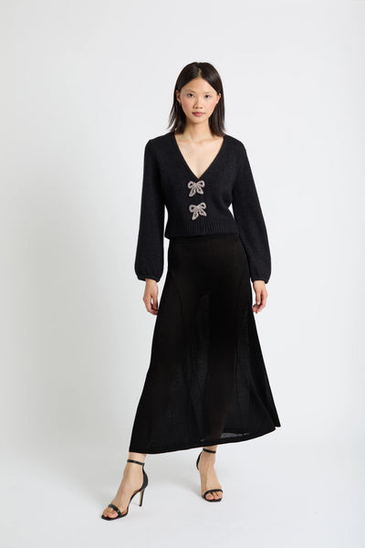 Woman wearing a black outfit with bow details on a white background