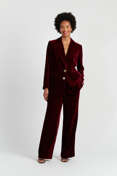 Woman wearing a burgundy velvet suit on a white background
