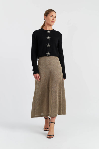 Woman wearing a black sweater with star patterns and a beige skirt on a white background