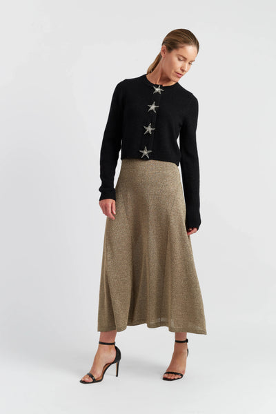 Woman wearing a black sweater with star patterns and a beige skirt on a white background
