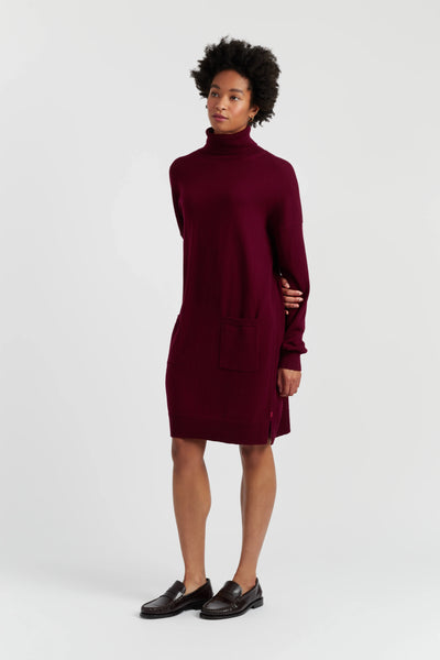 Woman wearing a burgundy turtleneck dress on a white background