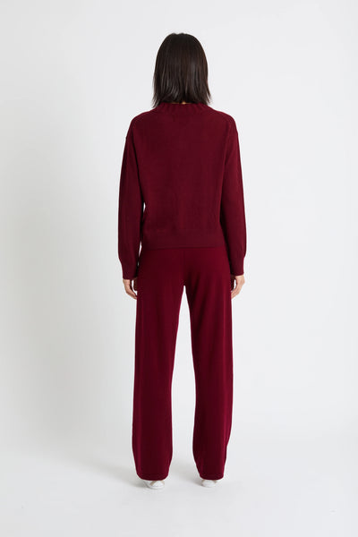 Person wearing a burgundy tracksuit on a white background