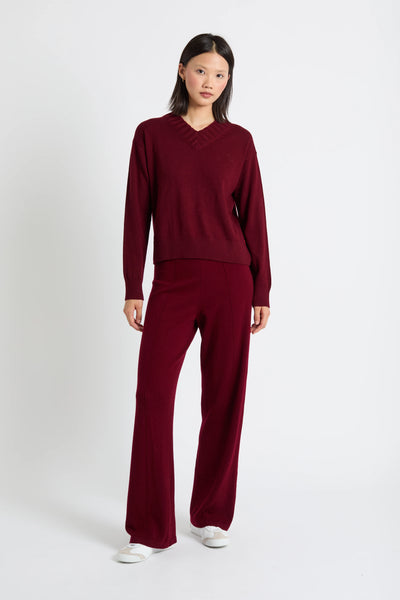 Person wearing a burgundy sweater and pants set on a white background