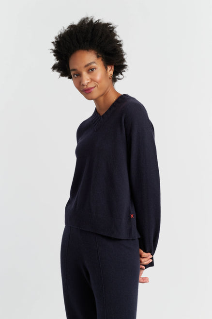 Woman wearing a navy blue outfit with a small red logo on a light gray background