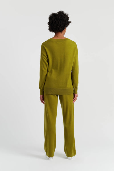 Person wearing a green sweater and pants set on a white background