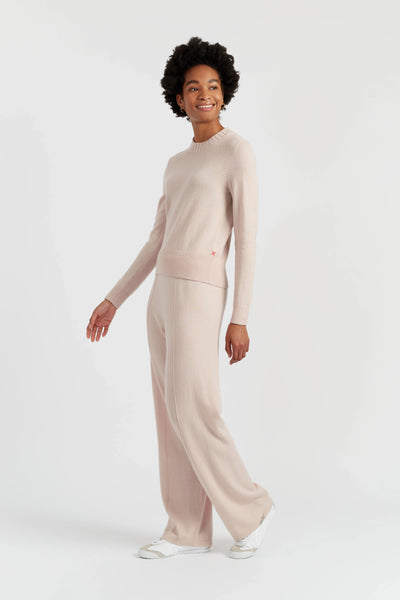 Woman wearing a beige long-sleeve top and pants on a white background