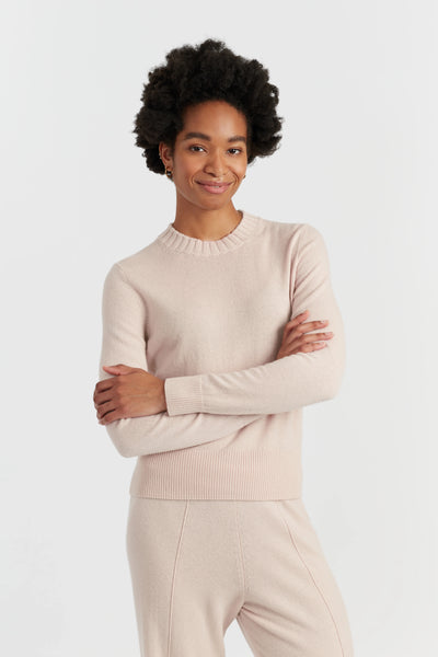 Woman wearing a beige sweater and pants on a white background