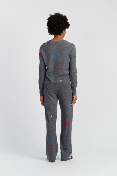 Person wearing a gray sweater and pants with colorful star patterns on a white background