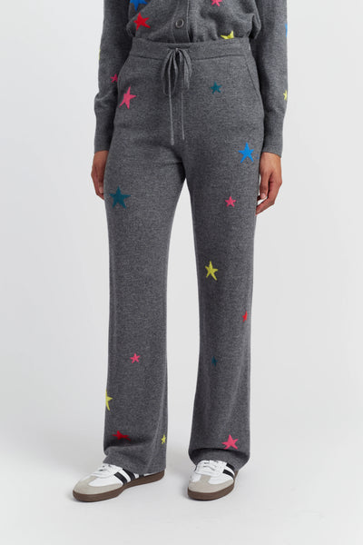 Person wearing gray sweatpants with colorful star patterns on a white background