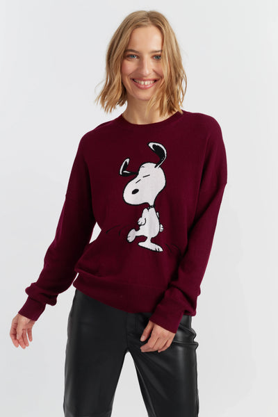 Woman wearing a maroon sweater with a white graphic design on a light gray background