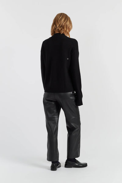Person wearing a black sweater and leather pants on a white background
