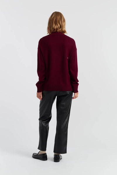 Person wearing a burgundy sweater and dark pants on a white background