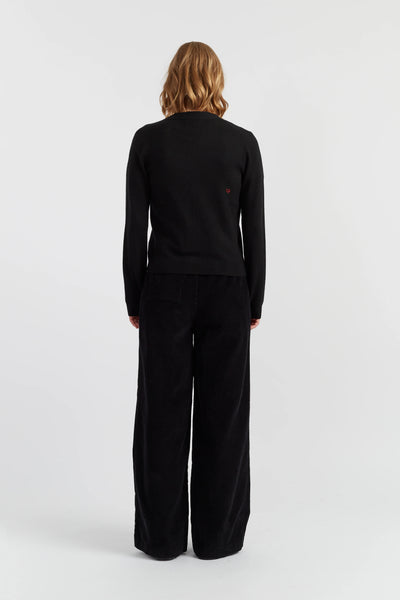 Person wearing a black outfit with wide-leg pants on a white background
