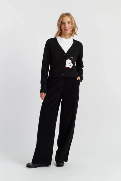 Woman wearing a black cardigan with a logo and black pants on a white background
