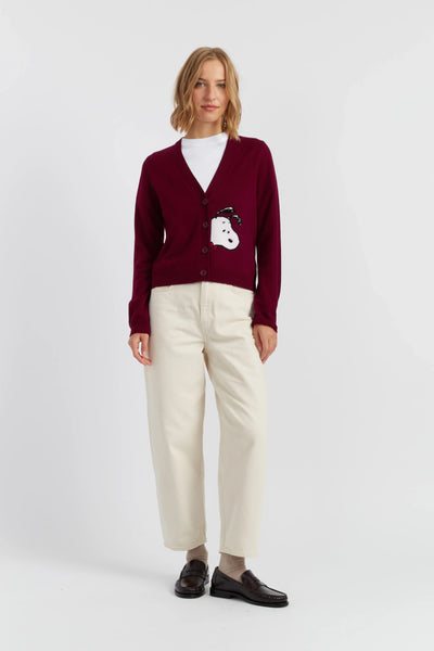 Person wearing a burgundy cardigan with a white shirt and beige pants on a white background
