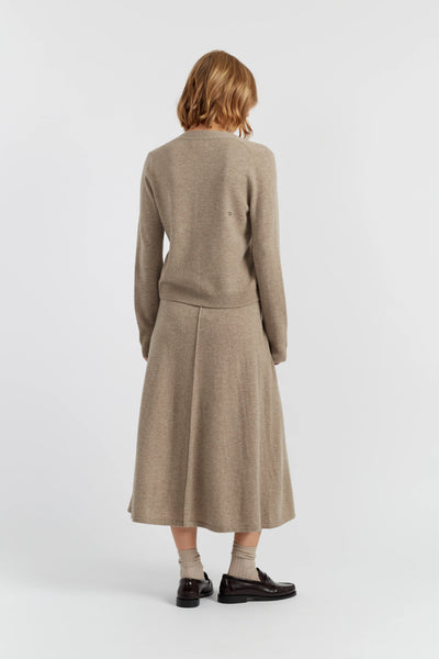 Woman wearing a beige sweater and skirt set on a white background