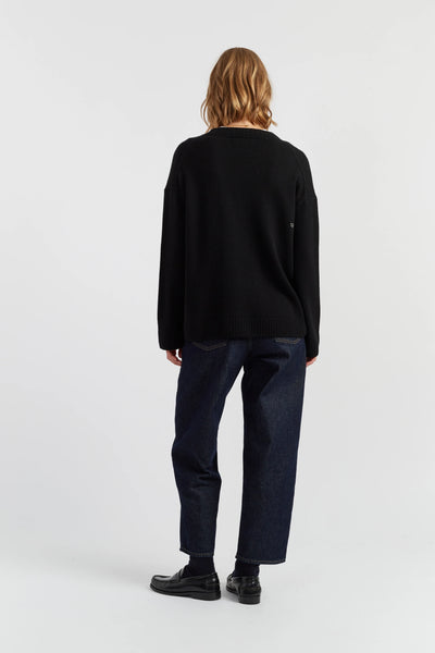 Person wearing a black sweater and dark pants on a white background