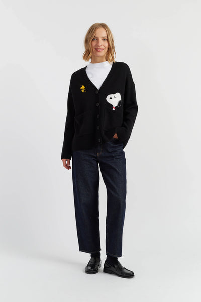 Person wearing a black cardigan with embroidered designs on a white background