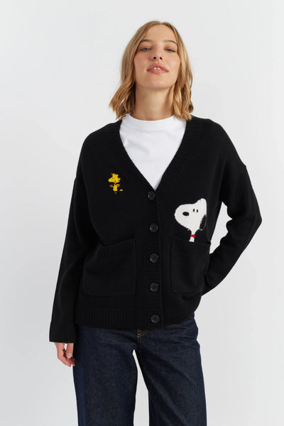 Person wearing a black cardigan with embroidered designs on a white background