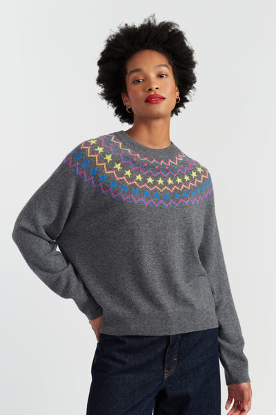 Woman wearing a gray sweater with colorful pattern on a white background