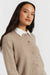 Woman wearing a beige cardigan over a white shirt on a plain background