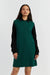 Woman wearing a green dress with black sleeves and collar on a white background