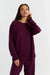 Woman wearing a burgundy sweater and pants on a white background