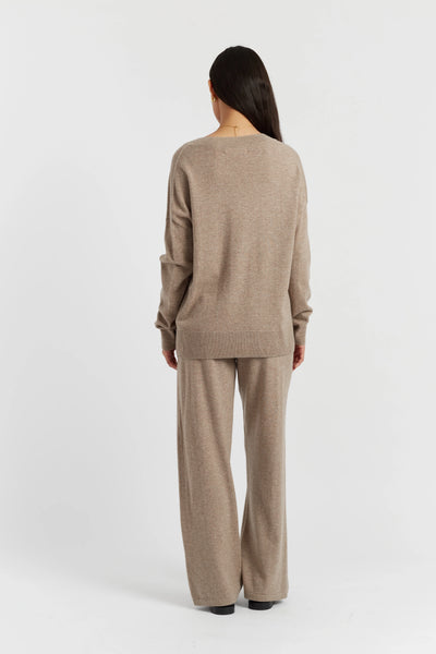 Person wearing a beige sweater and pants set on a white background