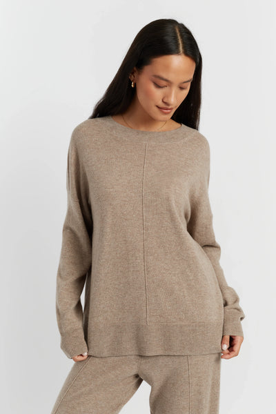 Woman wearing a beige sweater and pants on a white background