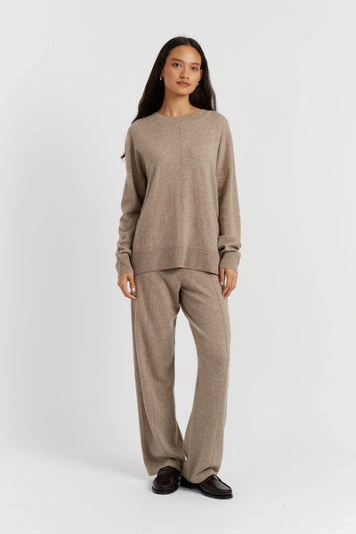 Woman wearing a beige sweater and pants set on a white background