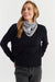 Woman wearing a black sweater and gray scarf with a dog design on a white background