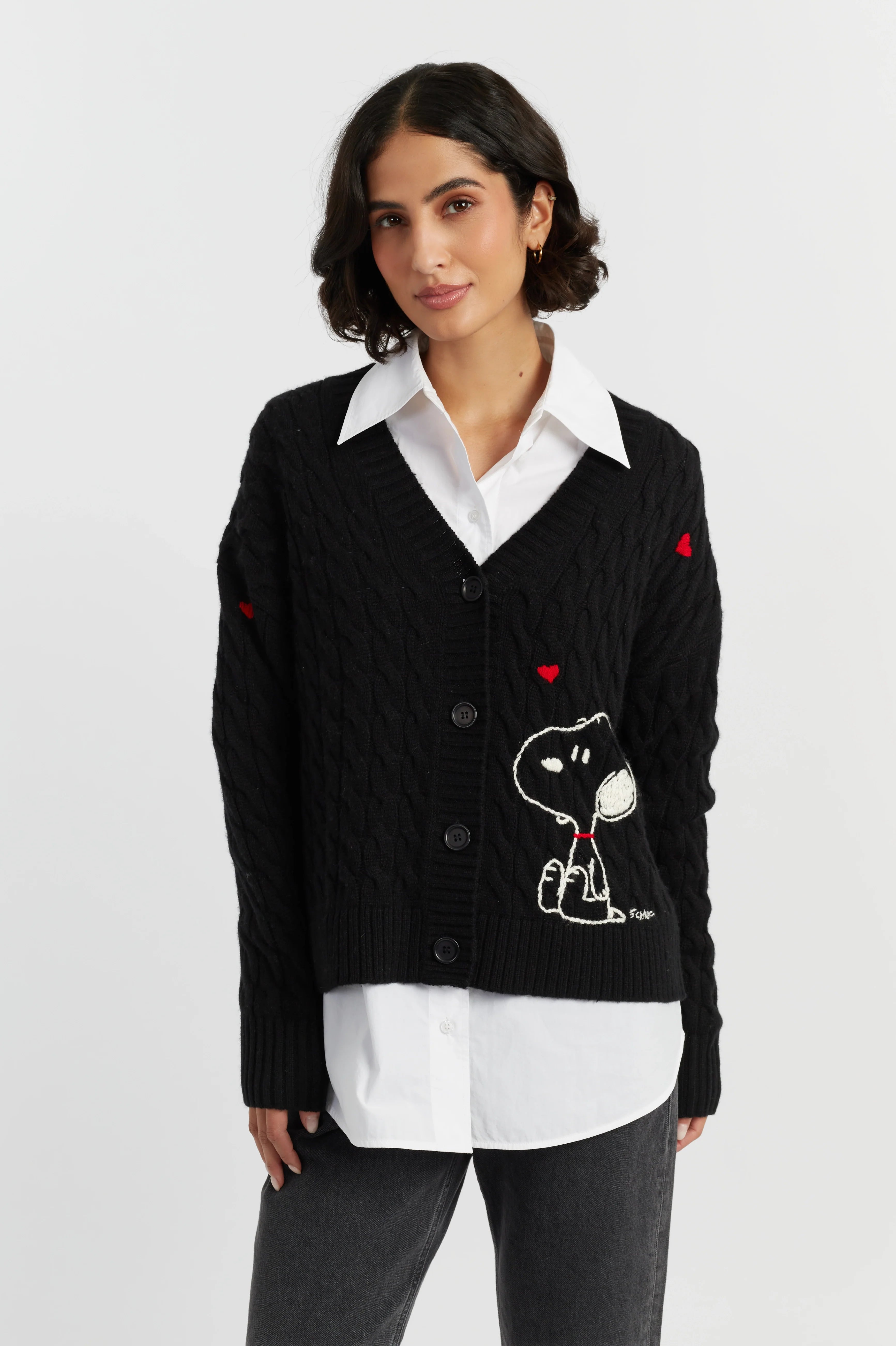 Woman wearing a black cardigan with a cartoon character design on a white background