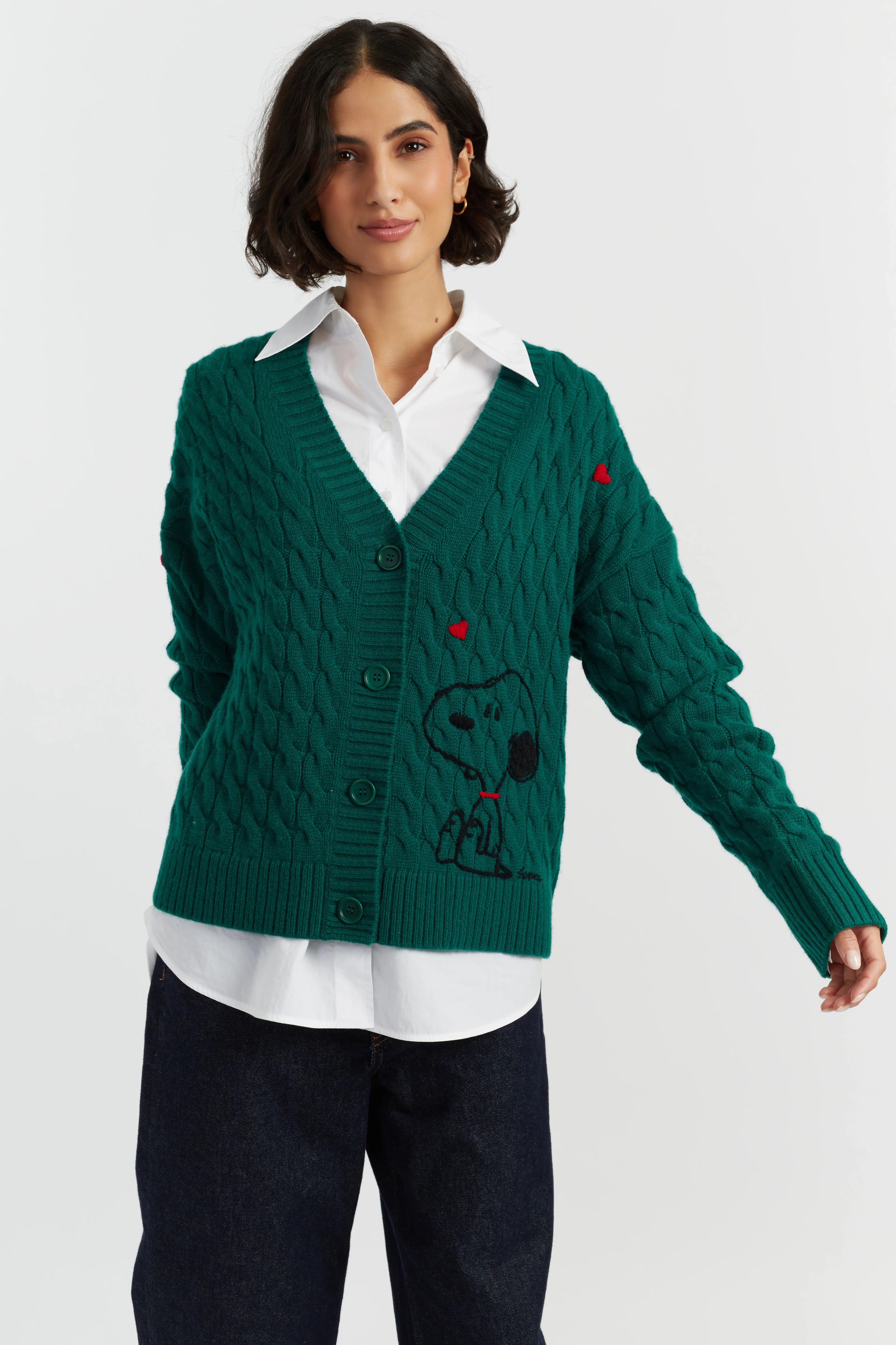 Woman wearing a green cardigan with a Snoopy design on a white background