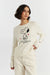 Woman wearing a white sweater with a Snoopy design on a plain background
